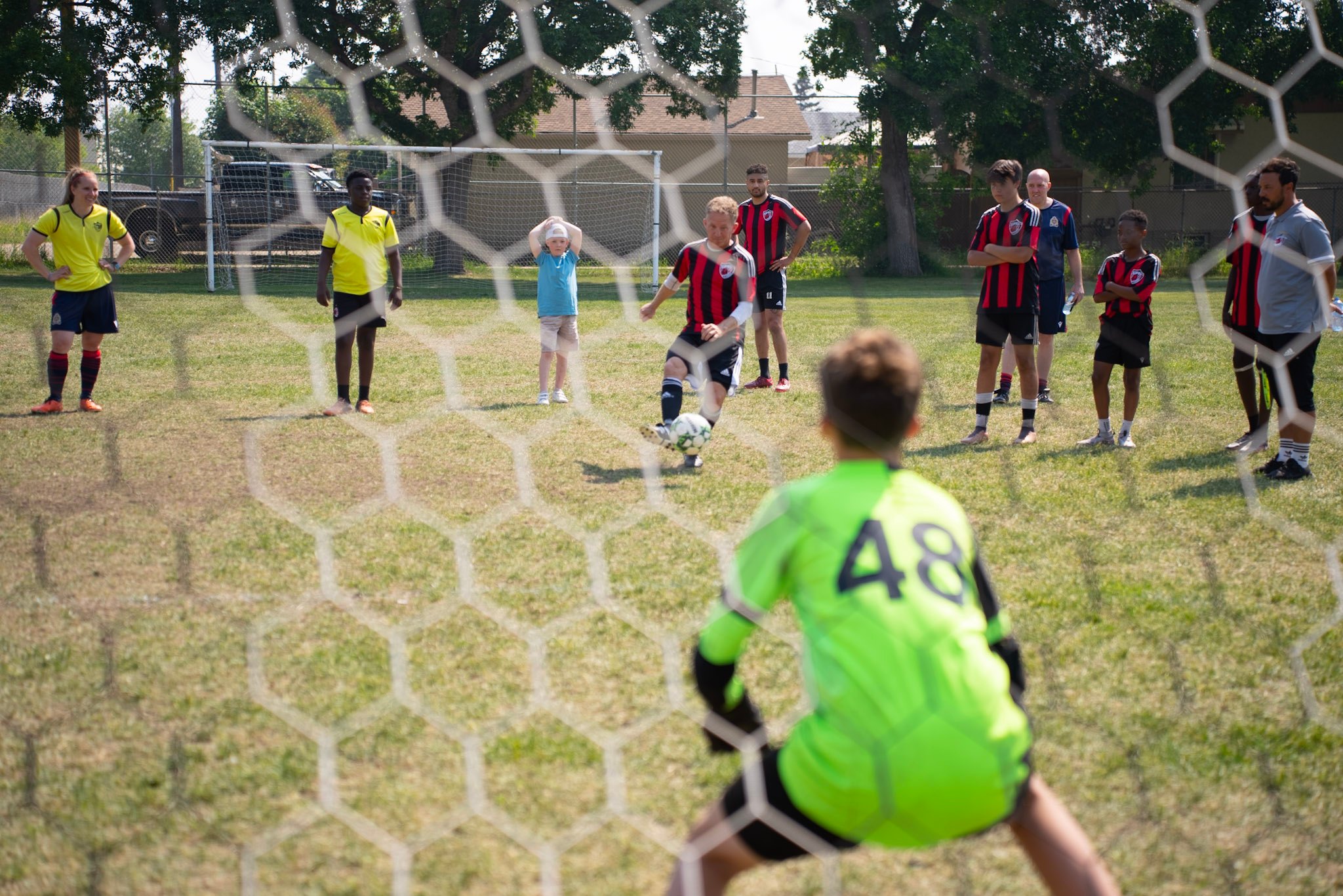 A view from behind the soccer net with a player trying to score on the goal keeper